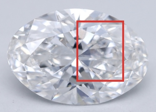 A close-up view of an oval-cut lab-grown diamond showing a section with noticeable crystal strain. The affected area, highlighted by a red box, appears blurry or 'roiled,' indicating an issue with transparency due to atomic-level irregularities.